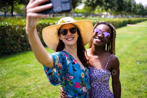 Preview: Two multiethnic women smiling to the mobile phone while taking a selfie
