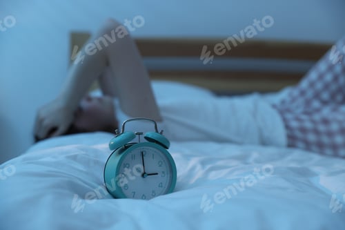 Visualização: Jovem frustrada que sofre de insônia na cama dentro de casa, concentre-se no despertador
