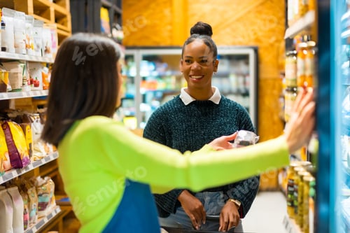 Preview: Saleswoman advising customer choosing food in organic supermarket