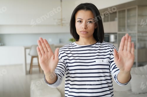 Preview: Serious young woman show stop gesture by palms, sign of prohibition, disagreement, rejection at home