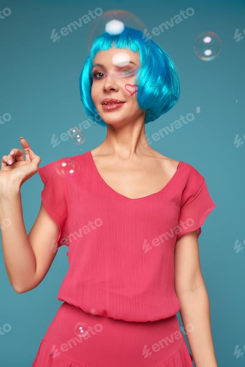 Preview: Beautiful young woman with blue wig and bright make-up in soap bubbles. Fashion model girl with