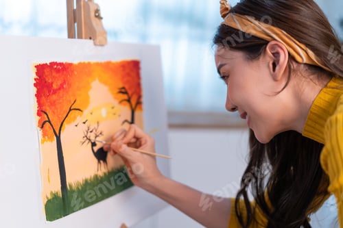 Preview: Asian young talented woman artist coloring on painting board in house.