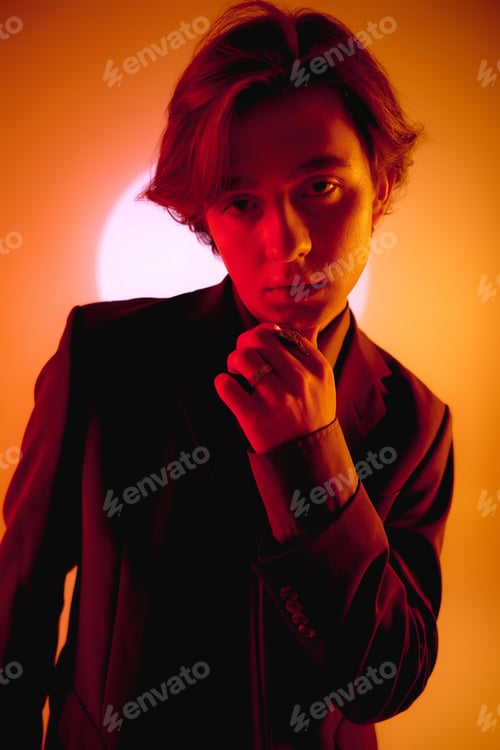 Preview: Young stylish man poses confidently against a vibrant sunset backdrop in an urban setting