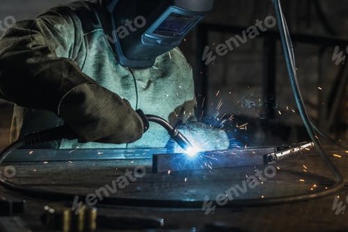 Preview: manual worker in protective helmet with welding torch working in workshop