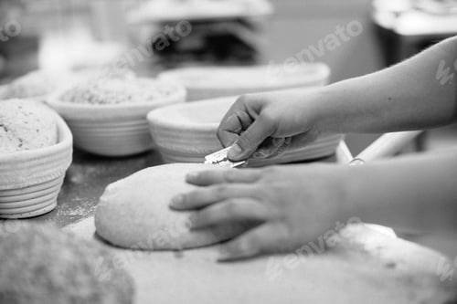 Preview: women's hands make an incision on a round dough before baking bread