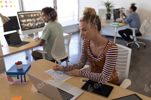 Preview: Concentrated female executive working on business graph at desk in office
