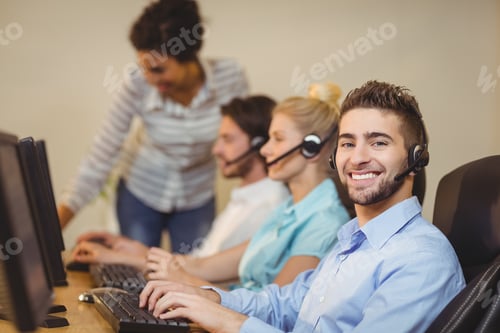 Preview: Portrait Of Male Employee With Coworkers Working In Call Center