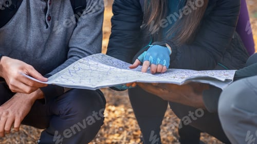 Preview: Three unrecognizable friends holding map, got lost at countryside