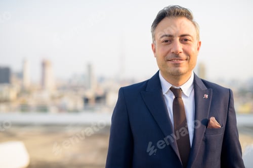 Preview: Face of happy mature businessman smiling against view of the city