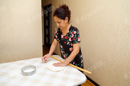 Visualização: Mulher estendendo a massa com rolo sobre uma mesa