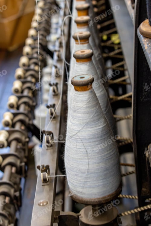 Preview: a machine is working on a white yarn spinning with cones