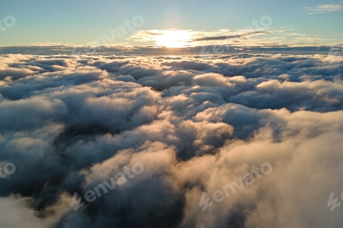 Preview: Aerial view from above at high altitude of dense puffy cumulus clouds flying in evening.