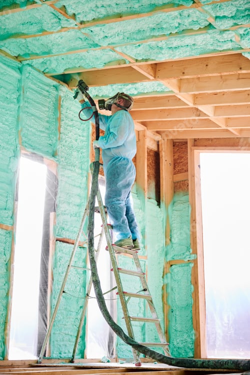 Preview: Worker spraying polyurethane foam for insulating wooden frame house.