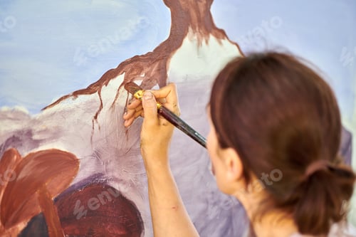 Visualização: A mão da artista feminina segura o pincel e desenha uma paisagem natural abstrata na tela