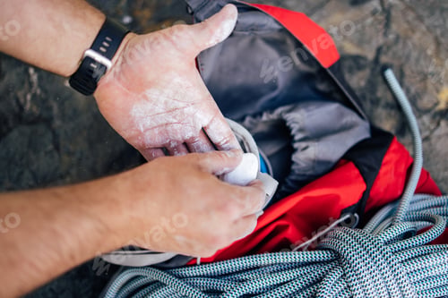 Preview: Climber Preparing Hands with Chalk Beside Equipment And Rope Outdoors on Rocks
