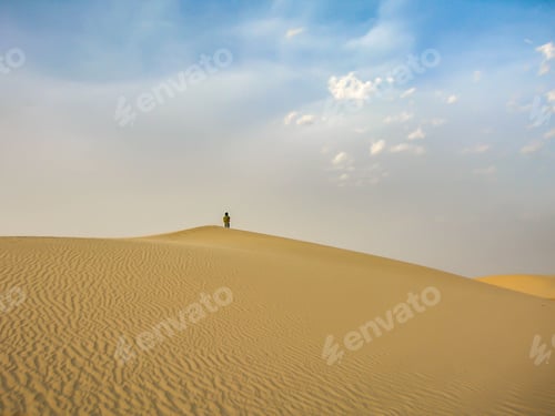 Preview: Lone Figure Standing Atop Desert Sand Dune