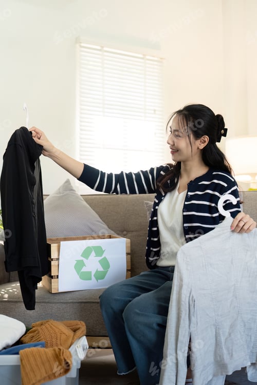 Preview: Woman pack box with used clothes for reuse. Reusing, recycling material and reducing waste in
