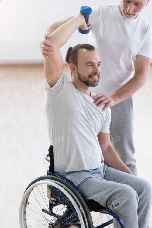 Preview: Delighted Disabled Man Exercising With His Assistant In The Gym