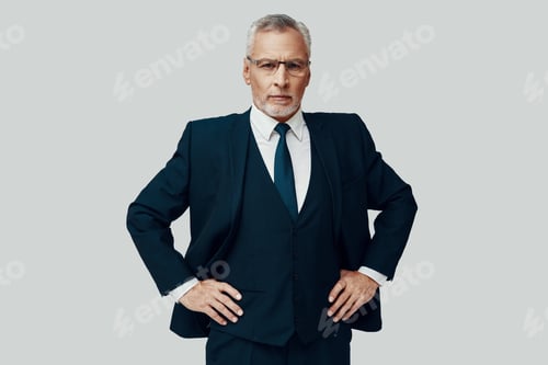 Preview: Handsome senior man in full suit looking at camera and keeping hands on hips