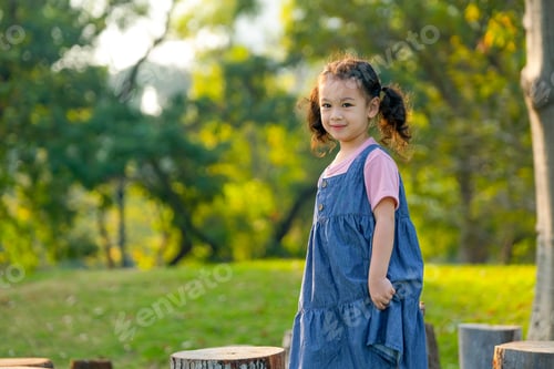 Preview: Young Asian little girl play alone in the garden with morning light.