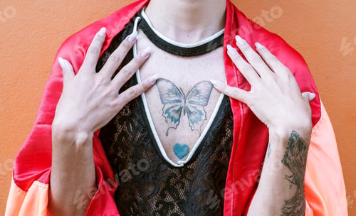Preview: Close-up of a young gay man with butterfly tattoo on his chest and draped with the gay flag