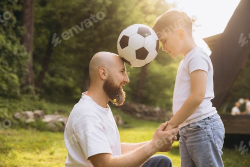 Preview: Father and son holding hands and playing with soccer ball celebrating father's day