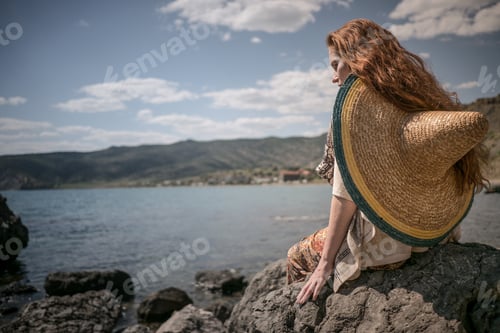 Preview: attractive young woman in ethnical costume on a field at sea