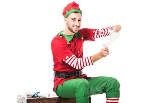 Preview: smiling man in christmas elf costume sitting and holding wishlist roll isolated on white
