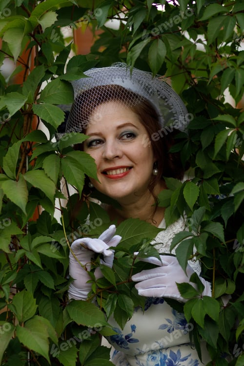Preview: A woman in vintage clothes and a hat stands against the background of a fountain in an autumn park