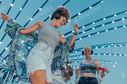 Preview: Young people dancing at silent disco with headphones and lights