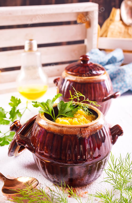 Preview: Corn porridge in a clay plate, a clay pot with porridge on a light background