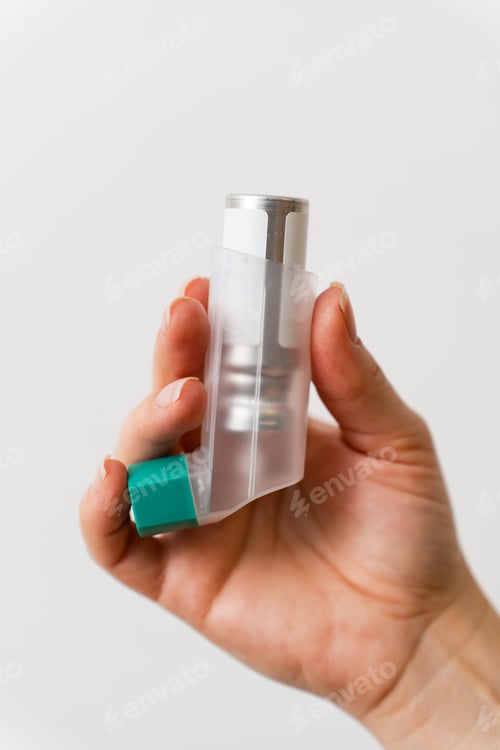 Preview: Male hand holding asthma inhaler close up on white background.