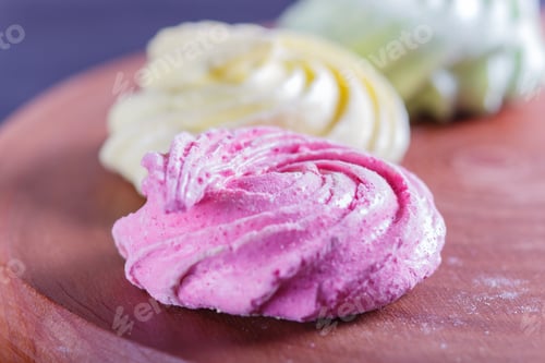 Preview: Colored meringues on wooden board.