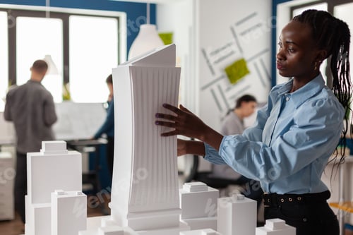 Preview: Architect standing at desk with white foam maquette of construction project