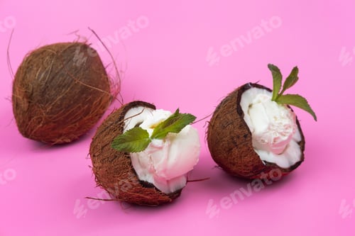 Preview: Vanilla ice cream balls in fresh coconut halves decorated with mint leaves on a pink background