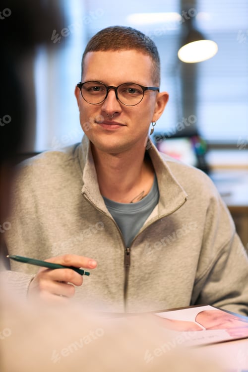 Preview: Portrait of Young Adult Caucasian Man Wearing Glasses Sitting at Desk Working