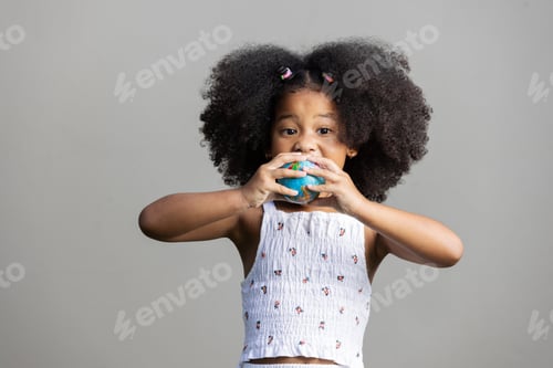 Preview: A young girl with a surprised expression holds a small globe ball in her hands.