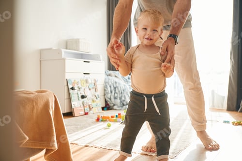 Preview: Learning to walk. Man is playing with his little son in the domestic room