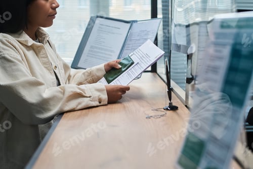 Preview: Young Adult Latin Woman Submitting Documents at Visa Center Reception Desk