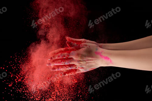 Preview: cropped view of adult woman holding red holi powder and clapping on black background