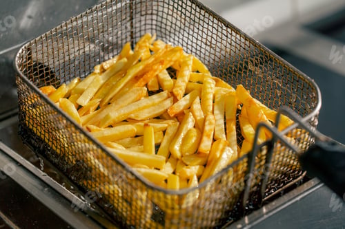 Preview: close-up in a professional kitchen the chef takes out french fries from the fryer