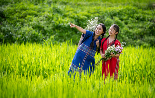 Preview: young girl dressed in traditional clothing, carrying a basket filled with flowers on her back. She i