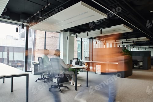 Preview: motion blur of man walking near business people working in open space office environment with high