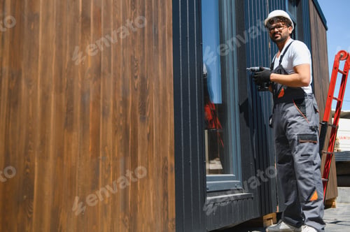 Preview: Construction worker securing modular house to truck for transportation