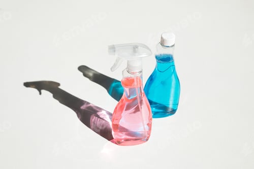 Preview: close-up view of plastic bottles with blue and pink cleaning fluids on white