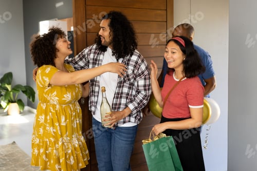 Preview: Friends celebrating at home, exchanging gifts and holding balloons with joy