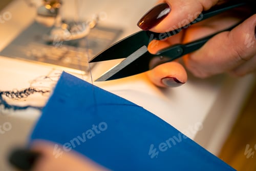 Preview: close-up in a sewing workshop scissors for working on fabric cut off blue thread