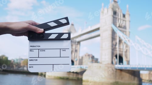 Preview: Hand is holding clapper board or movie slate with Tower Bridge background.