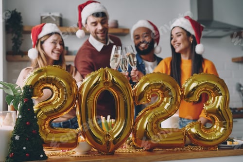 Visualização: Jovens felizes celebrando o Ano Novo com decoração dourada em primeiro plano