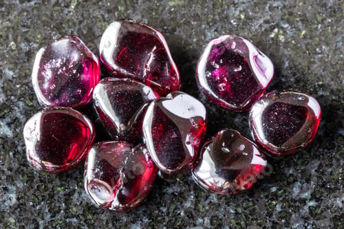Preview: many polished rhodolite crystals on black granite